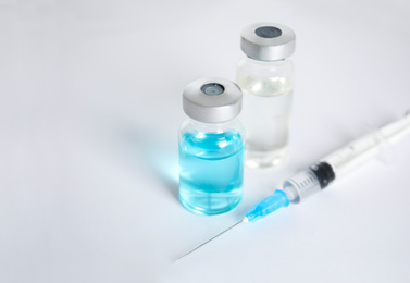Photo of Vials and syringe on light background. Vaccination and immunization