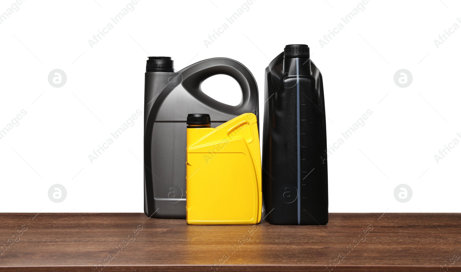 Photo of Motor oil in different containers on wooden table against white background