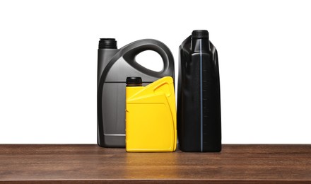 Photo of Motor oil in different containers on wooden table against white background