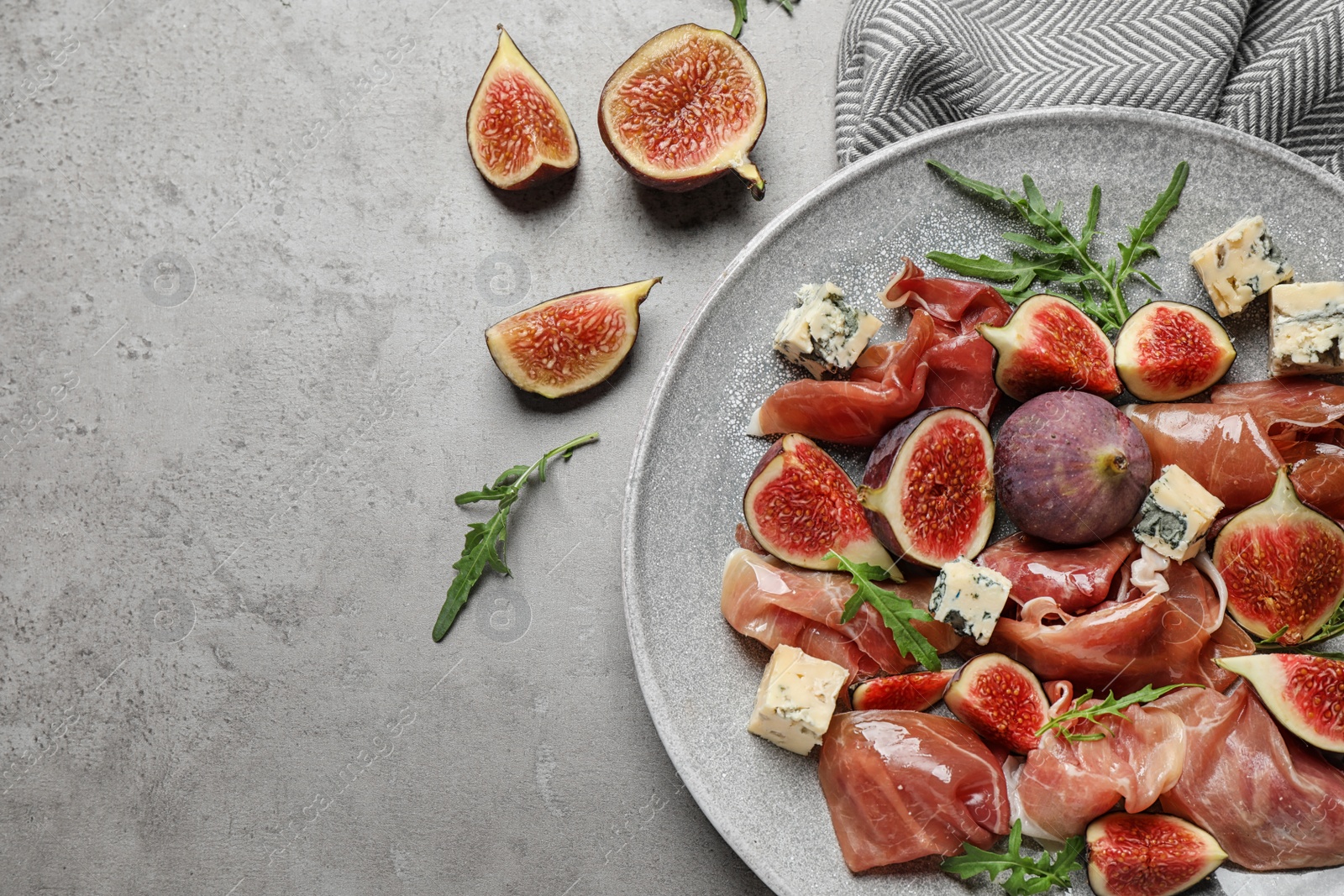 Photo of Plate with figs, prosciutto and cheese on light table, top view. Space for text