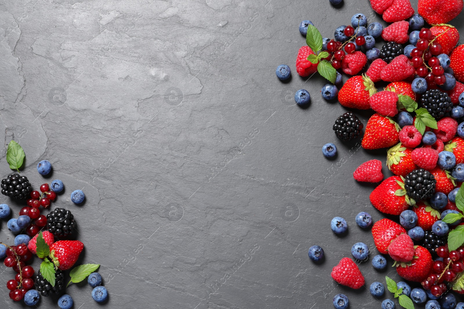 Photo of Many different fresh ripe berries on dark grey table, flat lay. Space for text