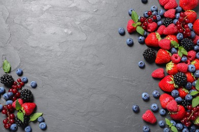 Photo of Many different fresh ripe berries on dark grey table, flat lay. Space for text