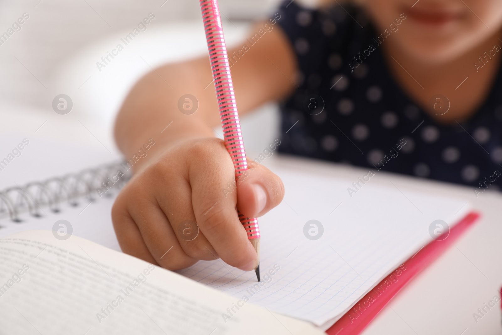 Photo of Little girl doing homework at table, closeup