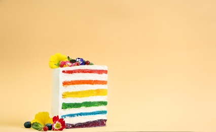 Photo of Slice of delicious rainbow cake with flowers on color background