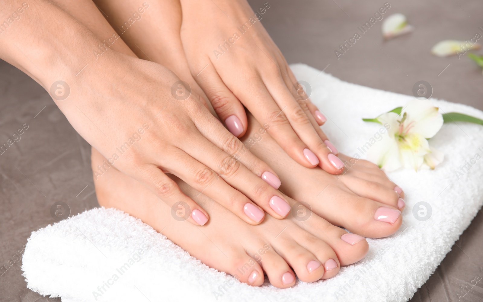 Photo of Woman touching her smooth feet and towel on grey background, closeup. Spa treatment