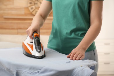 Woman ironing clean shirt at home, closeup