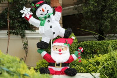 Photo of Funny snowman and Santa Claus outdoors. Festive Christmas decoration