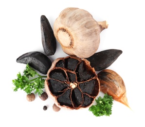 Aged black garlic with parsley on white background, view from above