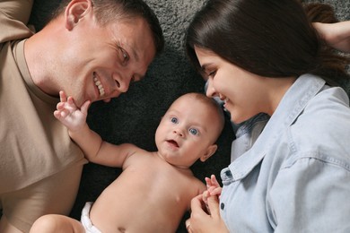 Photo of Happy family with their cute baby on floor, top view