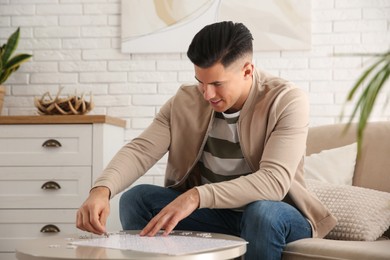 Photo of Man playing with puzzles at table in living room