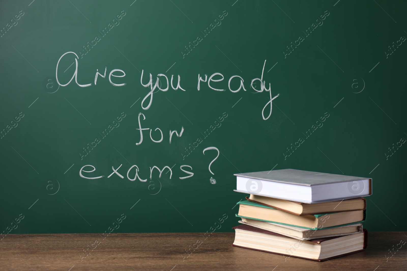 Photo of Books on wooden table near chalkboard with phrase Are You Ready For Exams