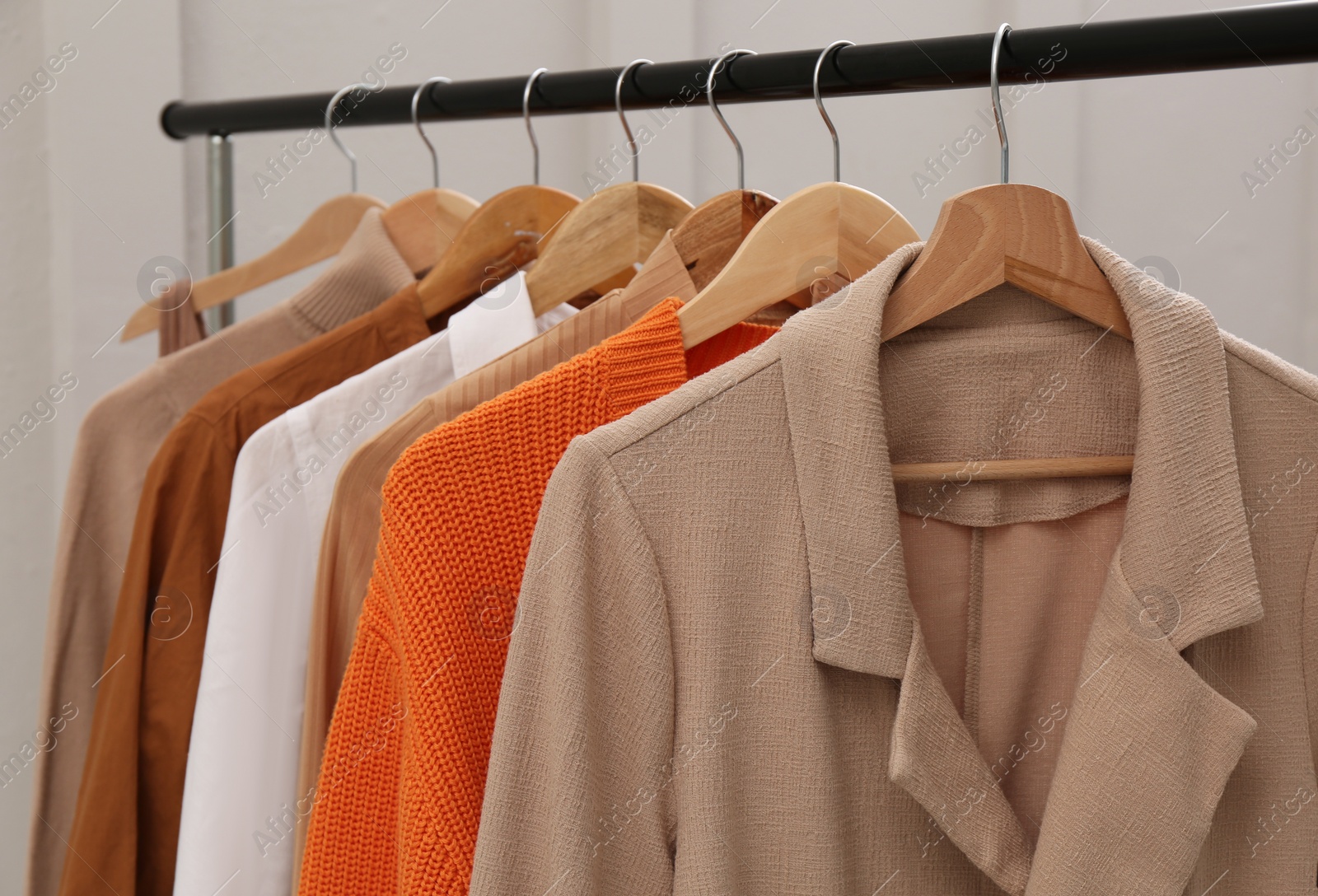 Photo of Rack with stylish women's clothes near light wall, closeup