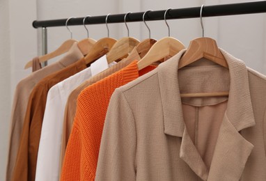 Rack with stylish women's clothes near light wall, closeup