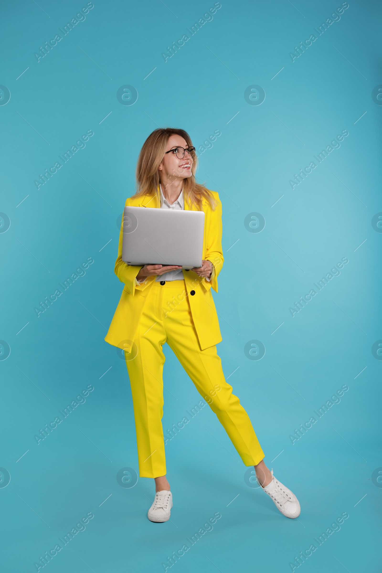 Photo of Young woman with modern laptop on light blue background