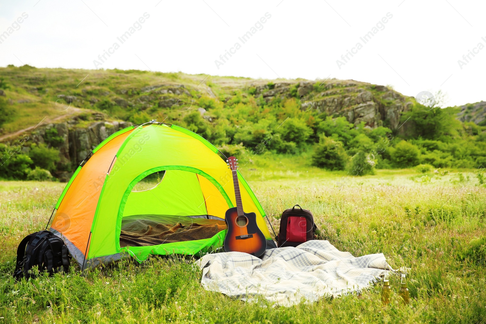 Photo of Camping tent, backpacks and guitar in wilderness