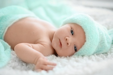 Photo of Adorable newborn baby in warm hat lying on bed