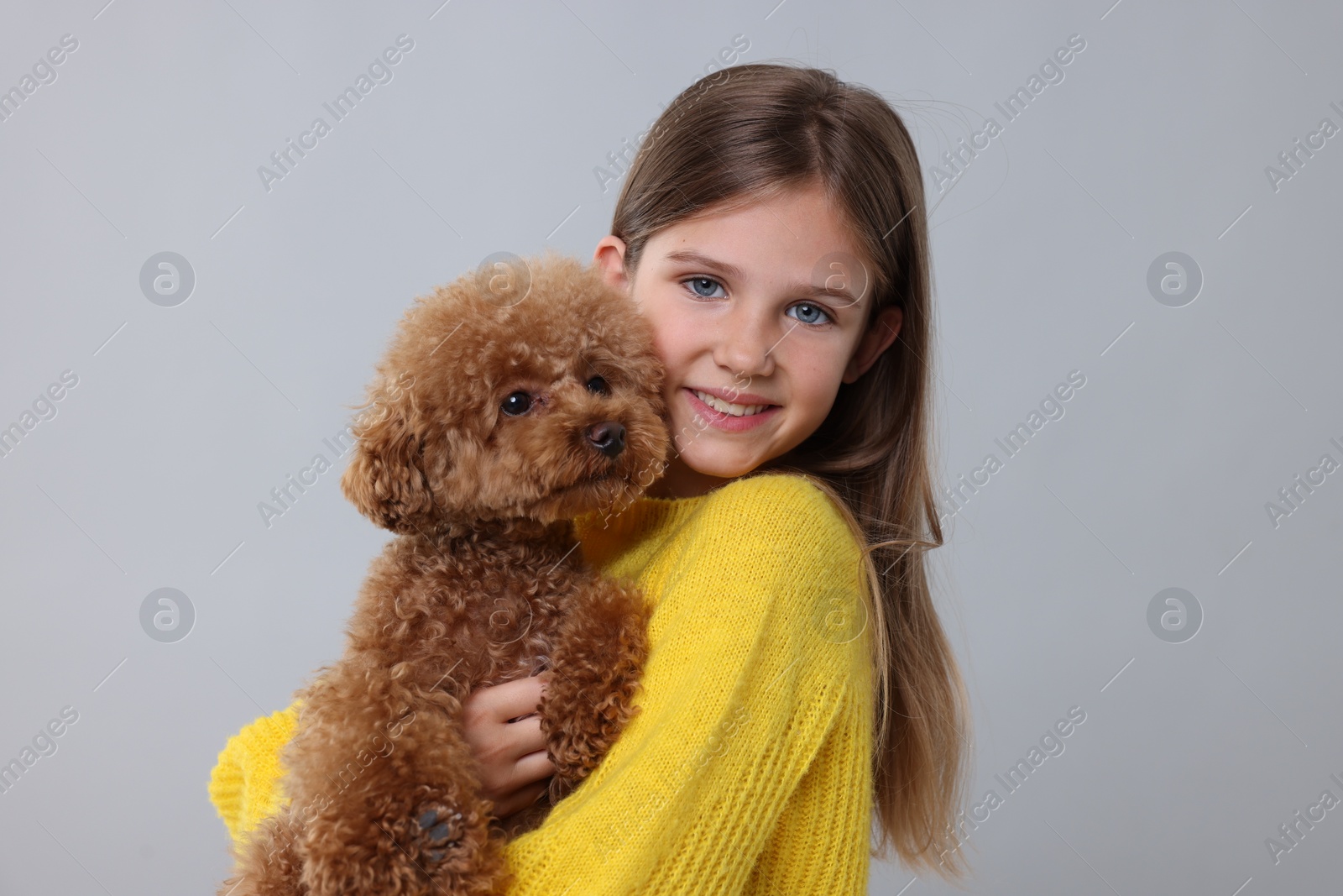 Photo of Little child with cute puppy on light grey background. Lovely pet