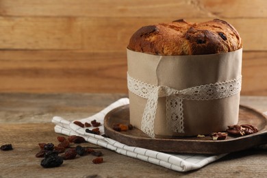 Photo of Delicious Panettone cake, walnuts and raisins on wooden table, space for text. Traditional Italian pastry