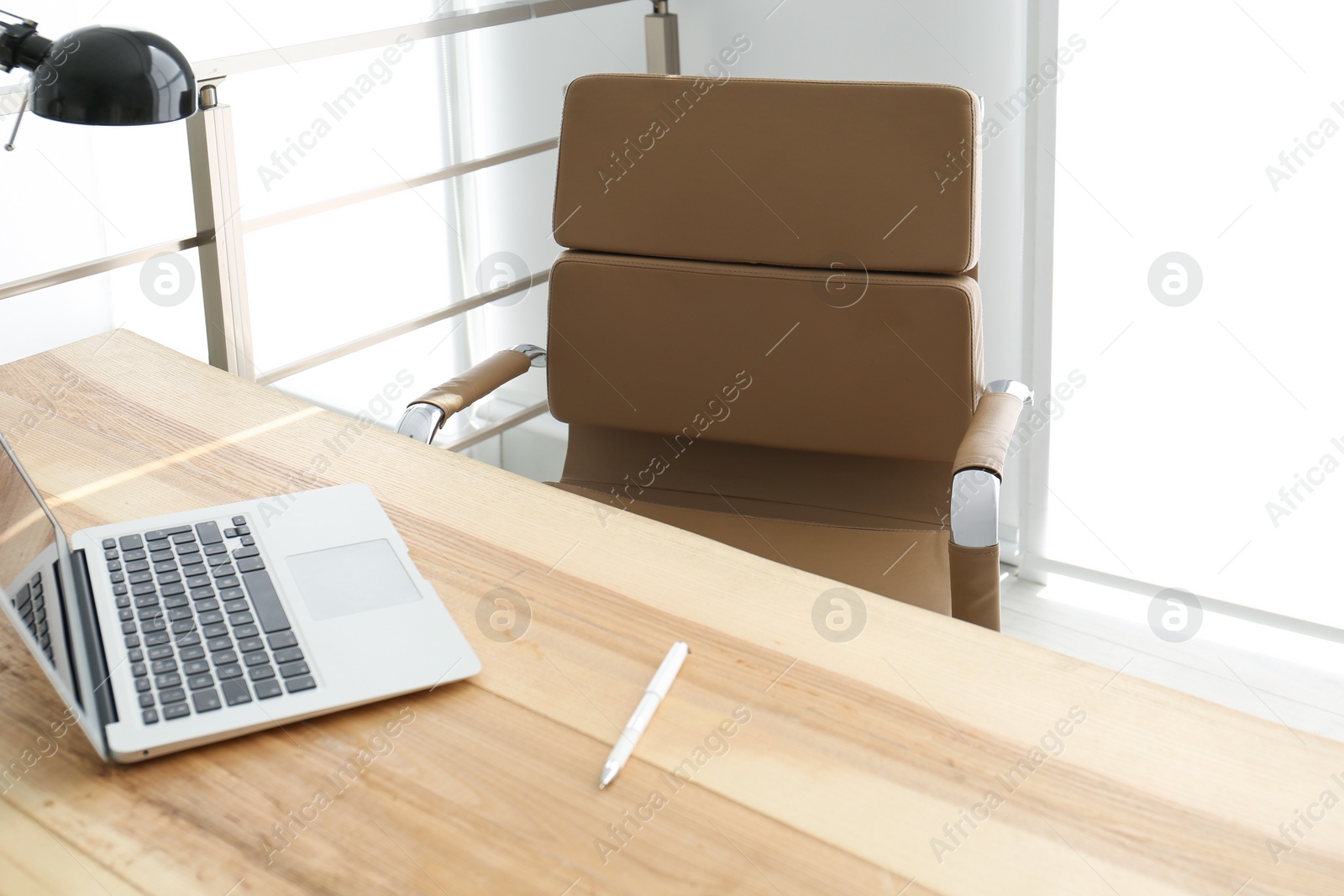 Photo of Comfortable workplace with office chair and wooden table