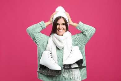 Happy woman with ice skates on pink background