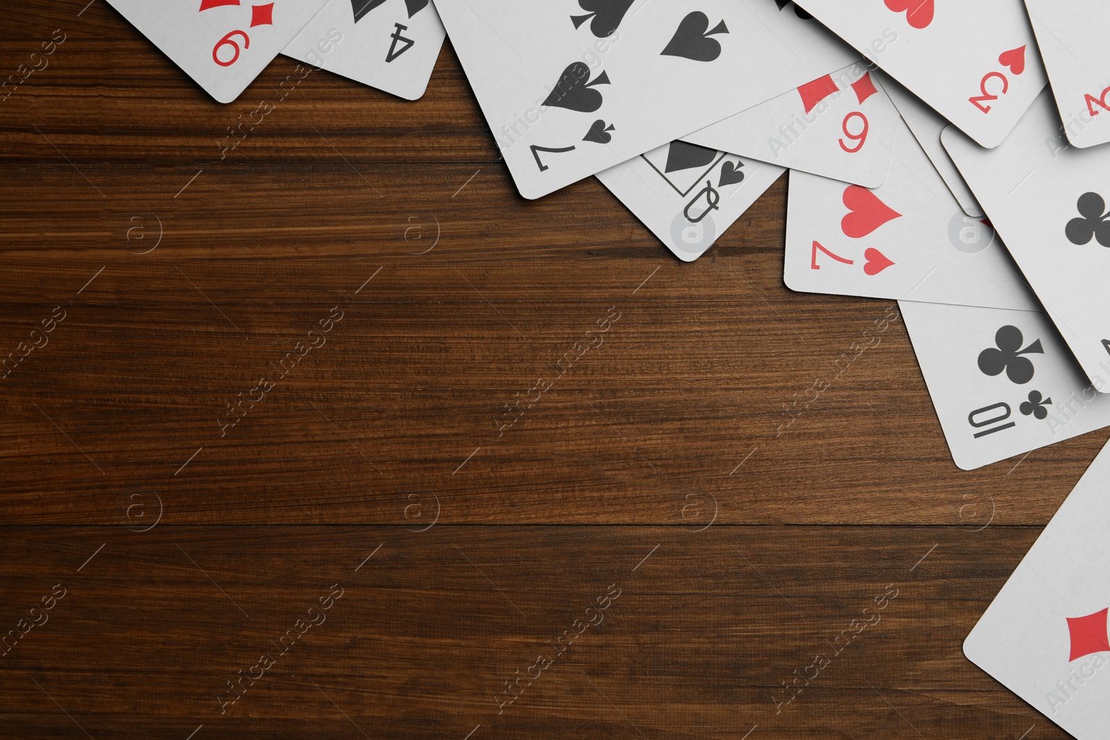 Photo of Playing cards on wooden table, flat lay. Space for text