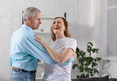 Happy senior couple dancing together at home