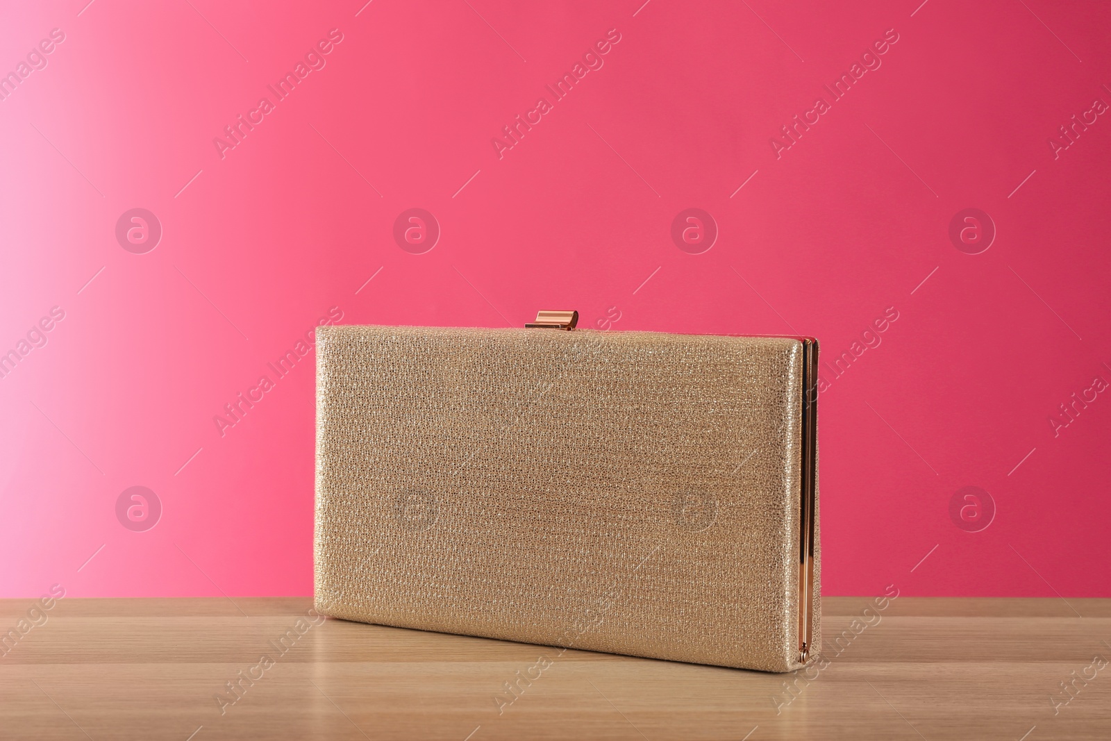 Photo of Stylish woman's purse on wooden table against pink background