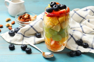 Photo of Delicious fruit salad, fresh berries and nuts on light blue wooden table