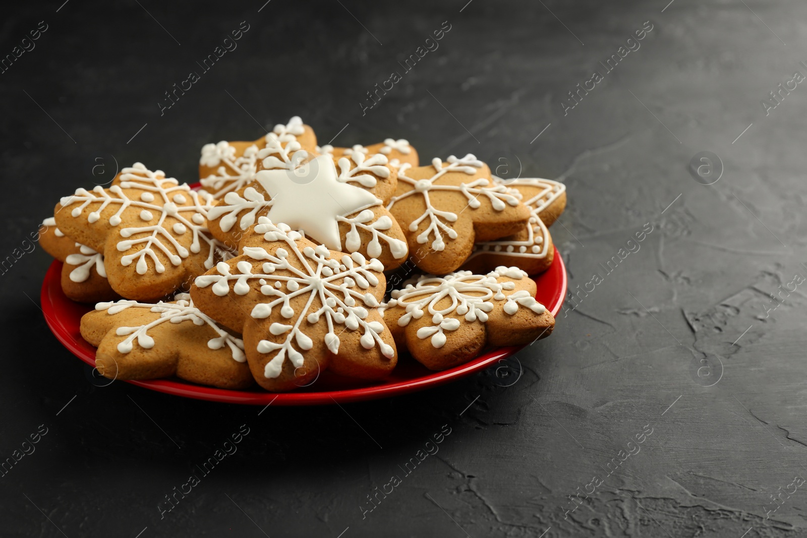 Photo of Tasty Christmas cookies with icing on black table. Space for text