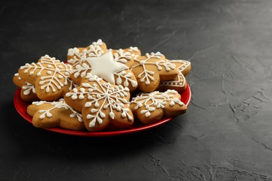 Tasty Christmas cookies with icing on black table. Space for text