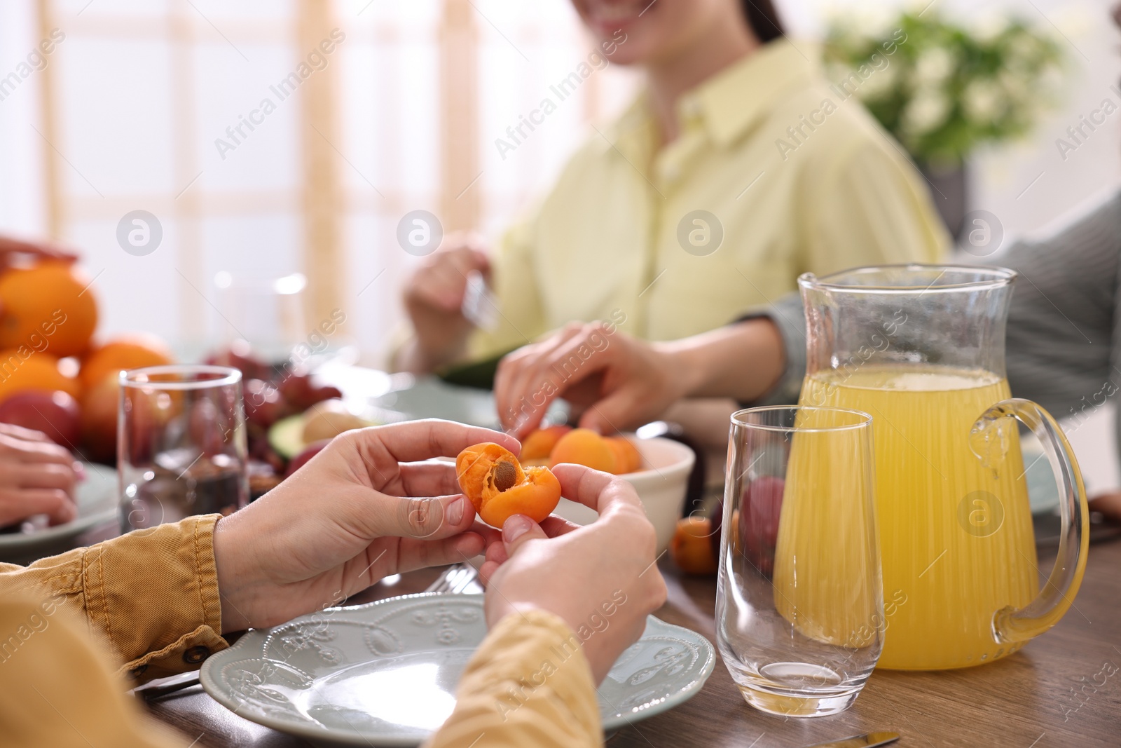 Photo of Vegetarian food. Friends eating fresh fruits at wooden table indoors, closeup