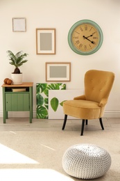 Tropical plant with green leaves and comfortable armchair in room interior
