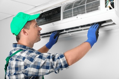 Photo of Male technician installing air conditioner indoors