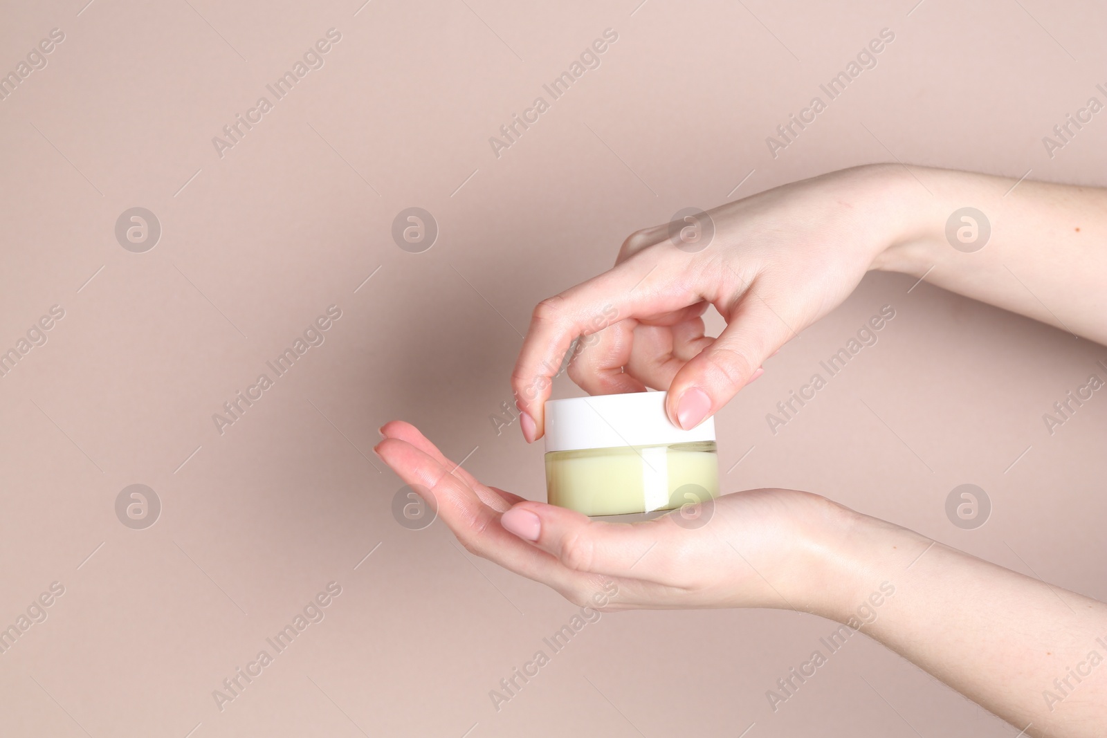 Photo of Woman with jar of cream on beige background, closeup