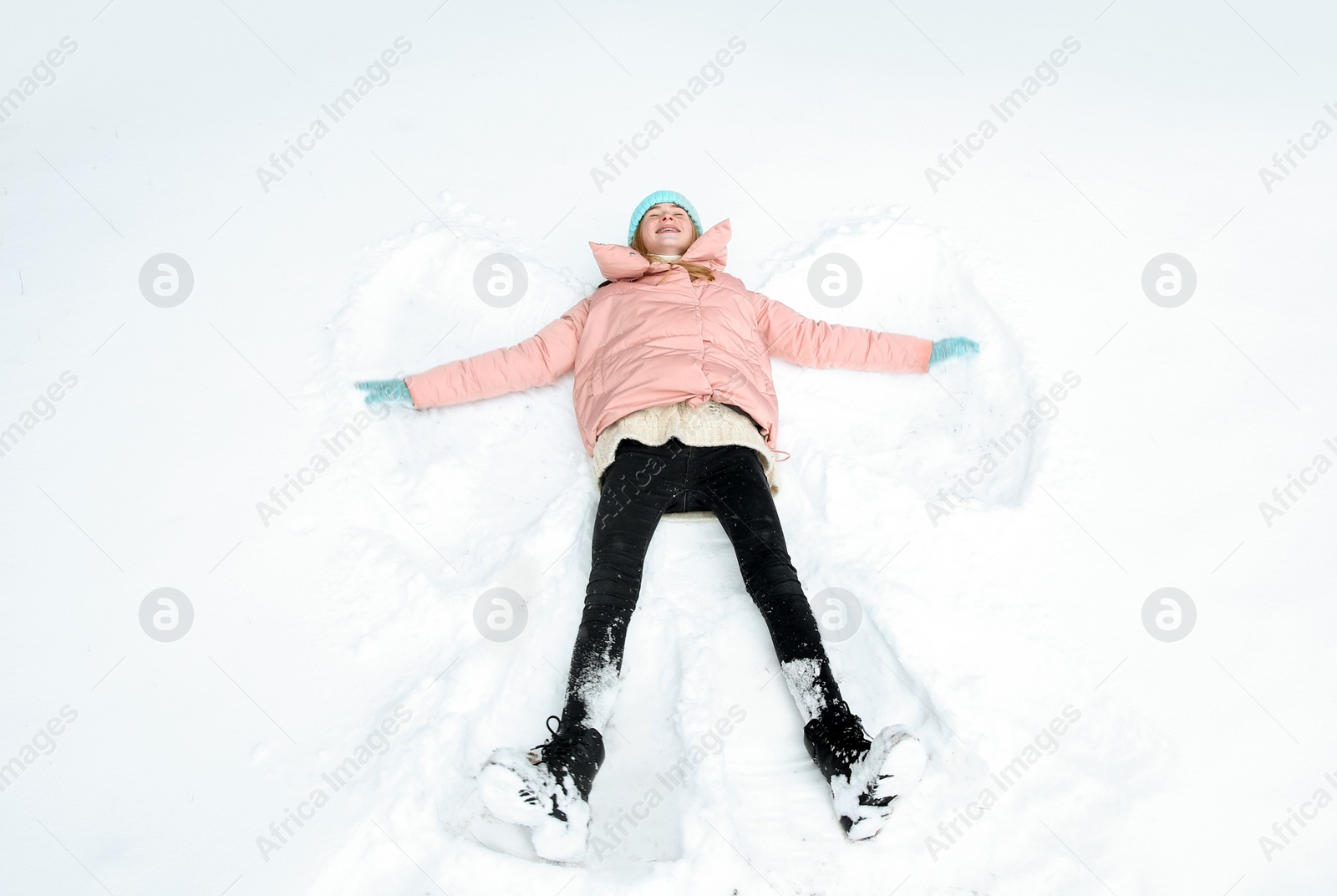 Photo of Teenage girl making snow angel on winter day