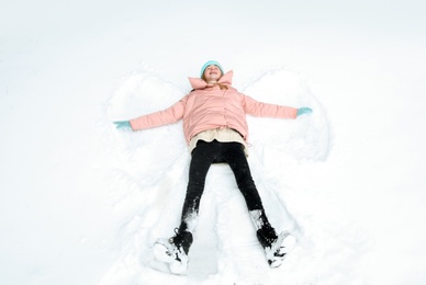 Photo of Teenage girl making snow angel on winter day