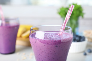 Glasses of delicious blueberry smoothie served on kitchen table, closeup