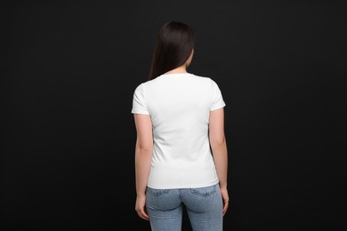 Photo of Woman wearing white t-shirt on black background, back view