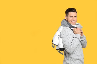 Happy man with ice skates on yellow background. Space for text