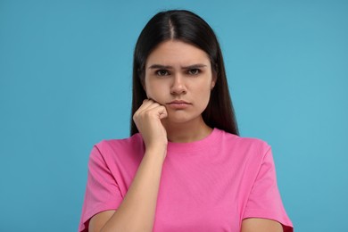 Portrait of resentful woman on light blue background