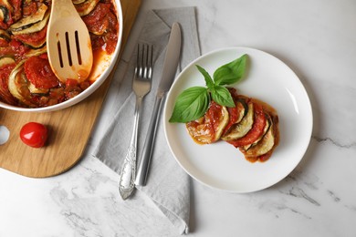 Photo of Delicious ratatouille served with basil on white marble table, flat lay