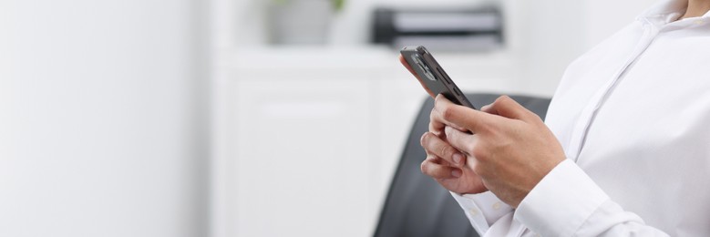 Woman typing message on mobile phone indoors, closeup. Banner design with space for text