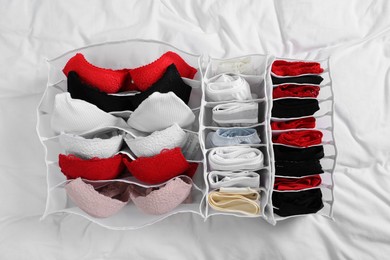 Photo of Organizer with stylish women's underwear on bed, top view