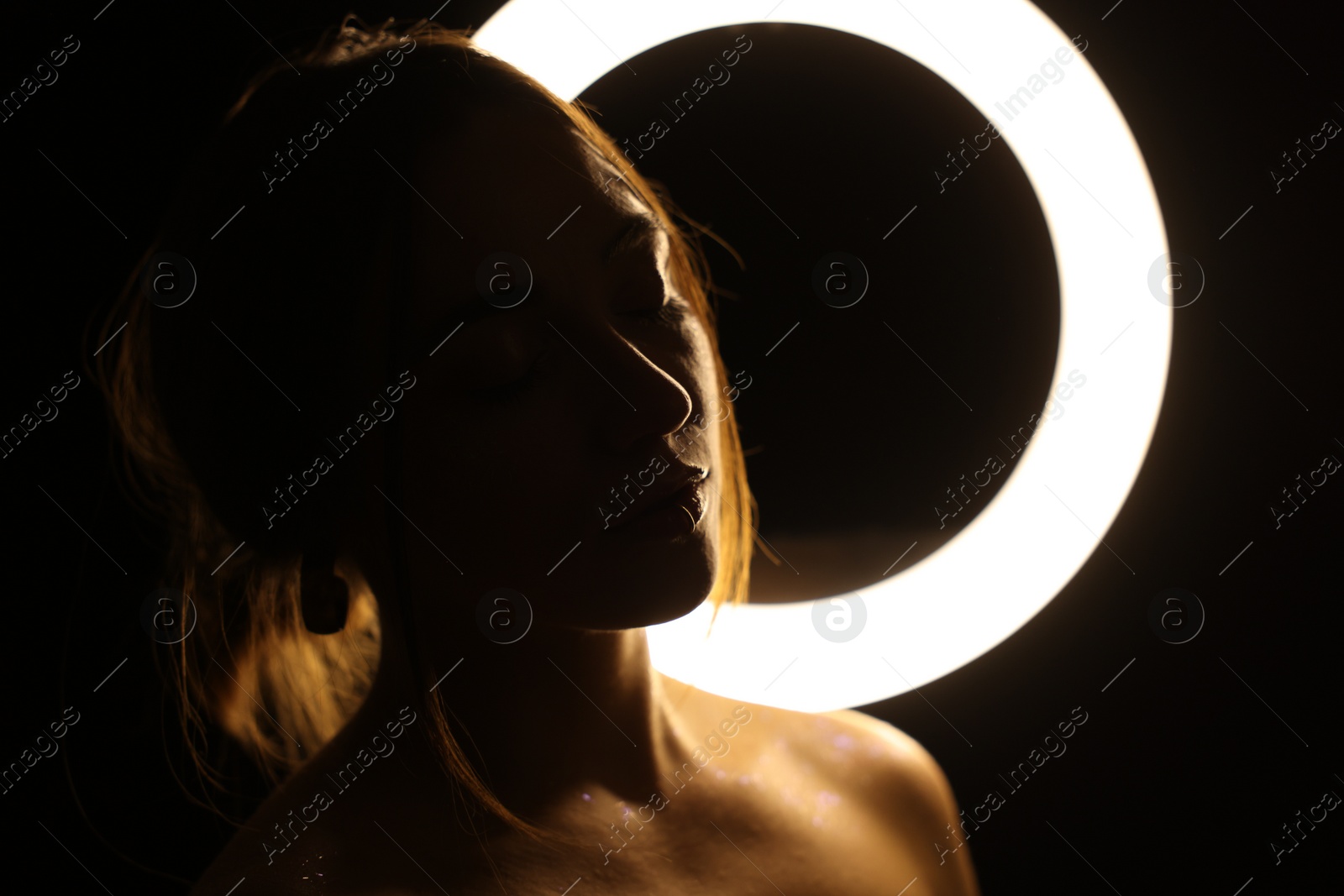 Photo of Beautiful woman and ring lamp in darkness