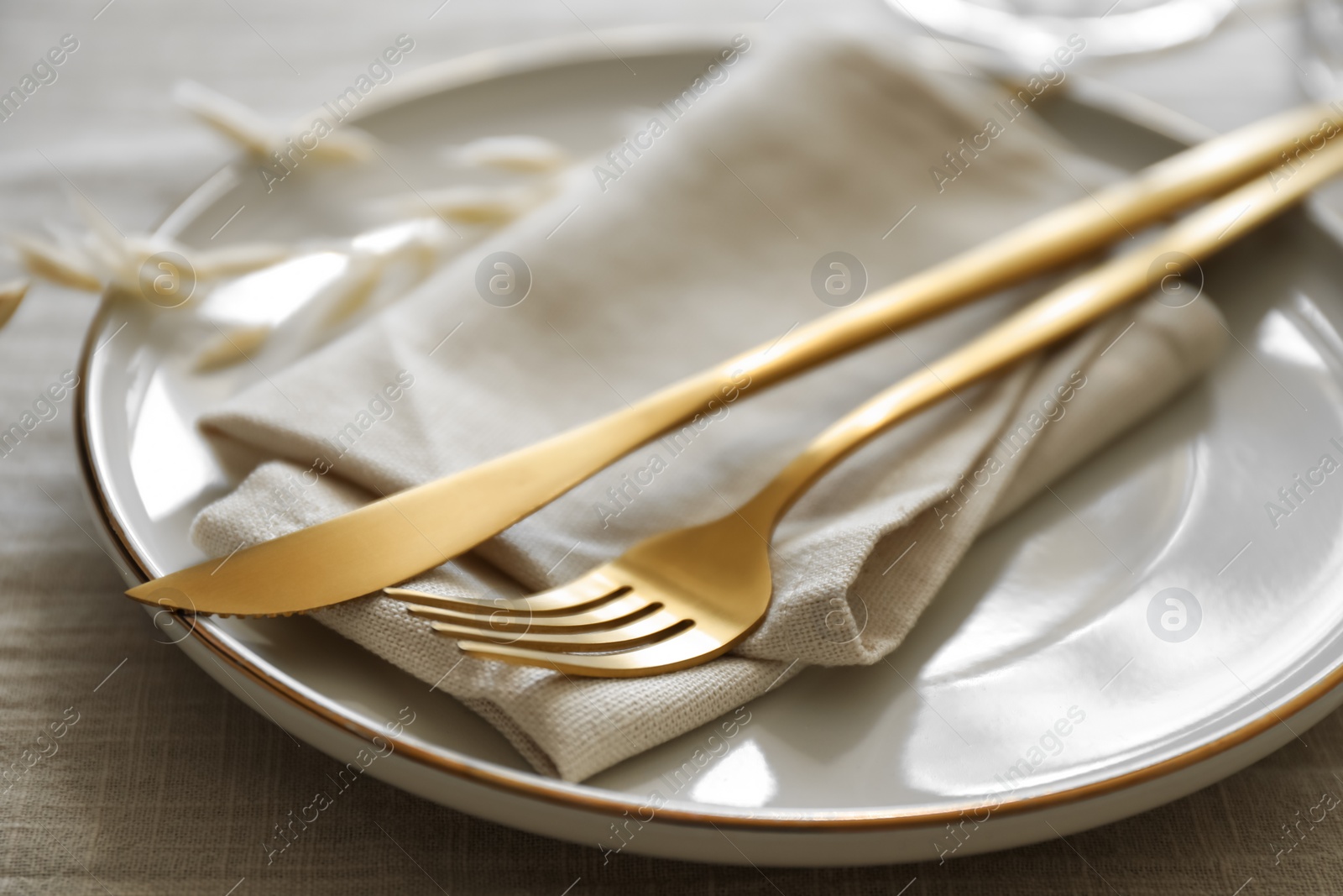 Photo of Stylish setting with cutlery, napkin and plate on light table, closeup