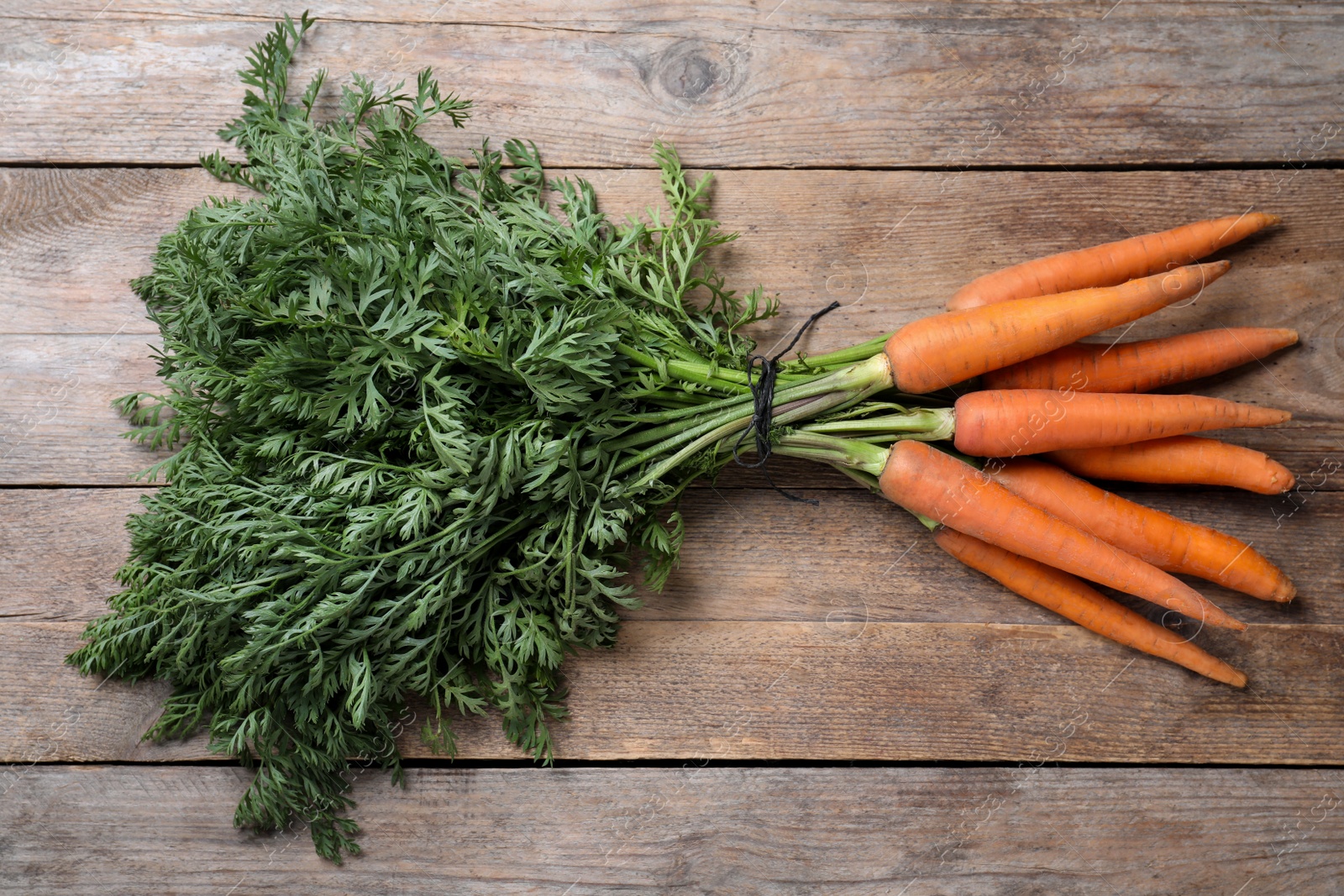 Photo of Ripe carrots on wooden table, top view