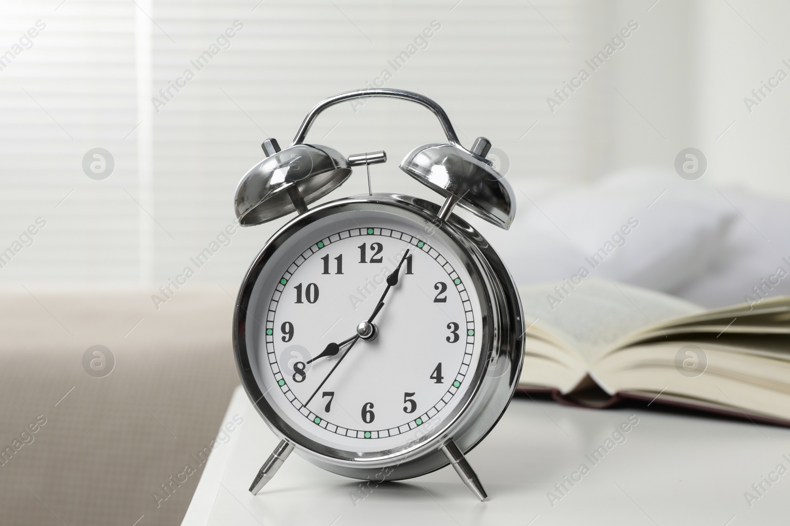 Photo of Silver alarm clock on white nightstand in bedroom