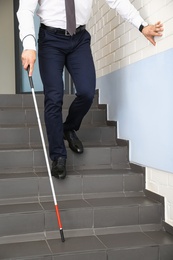 Blind person with long cane going down stairs, closeup