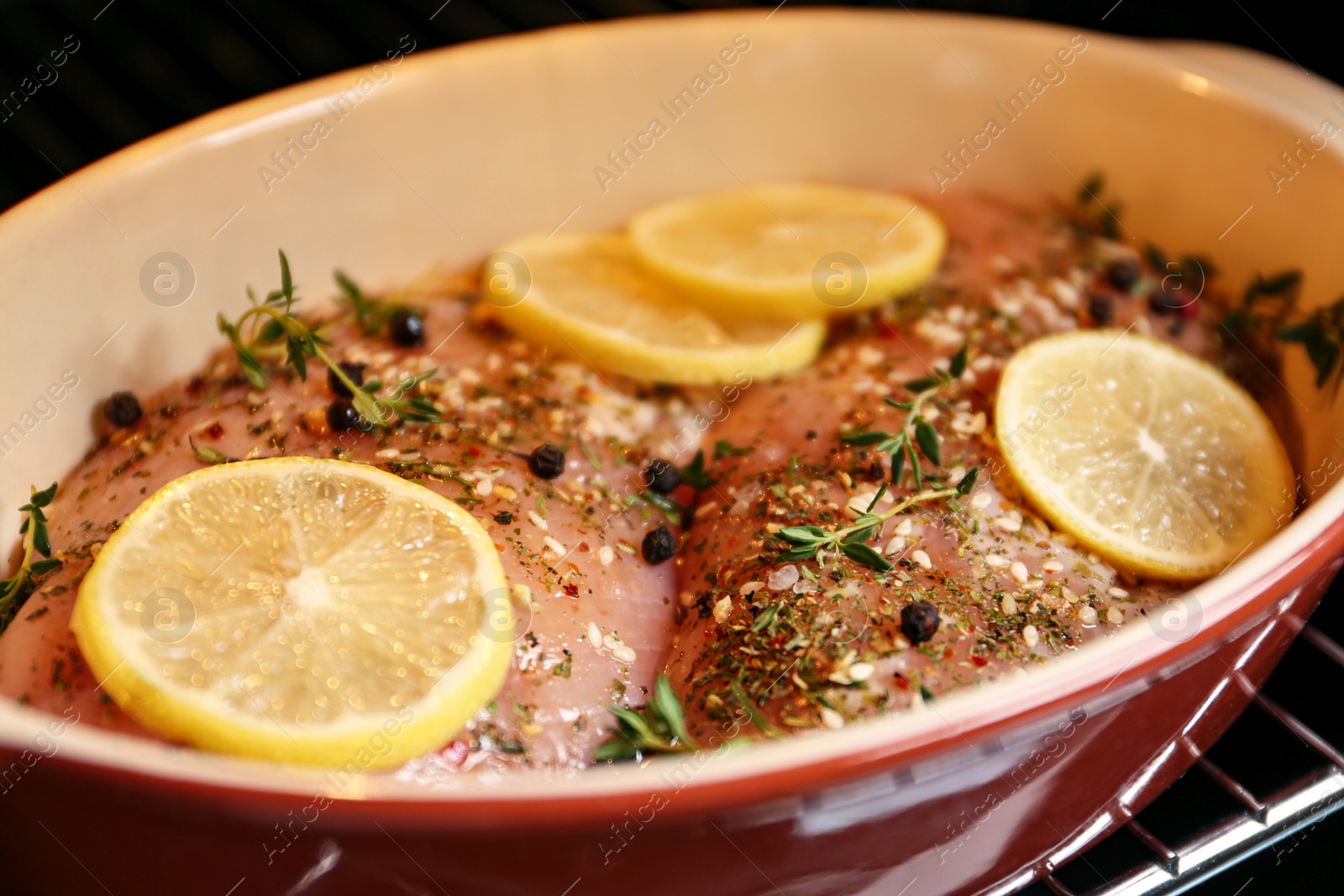 Photo of Chicken breasts with lemon and rosemary in baking dish, closeup