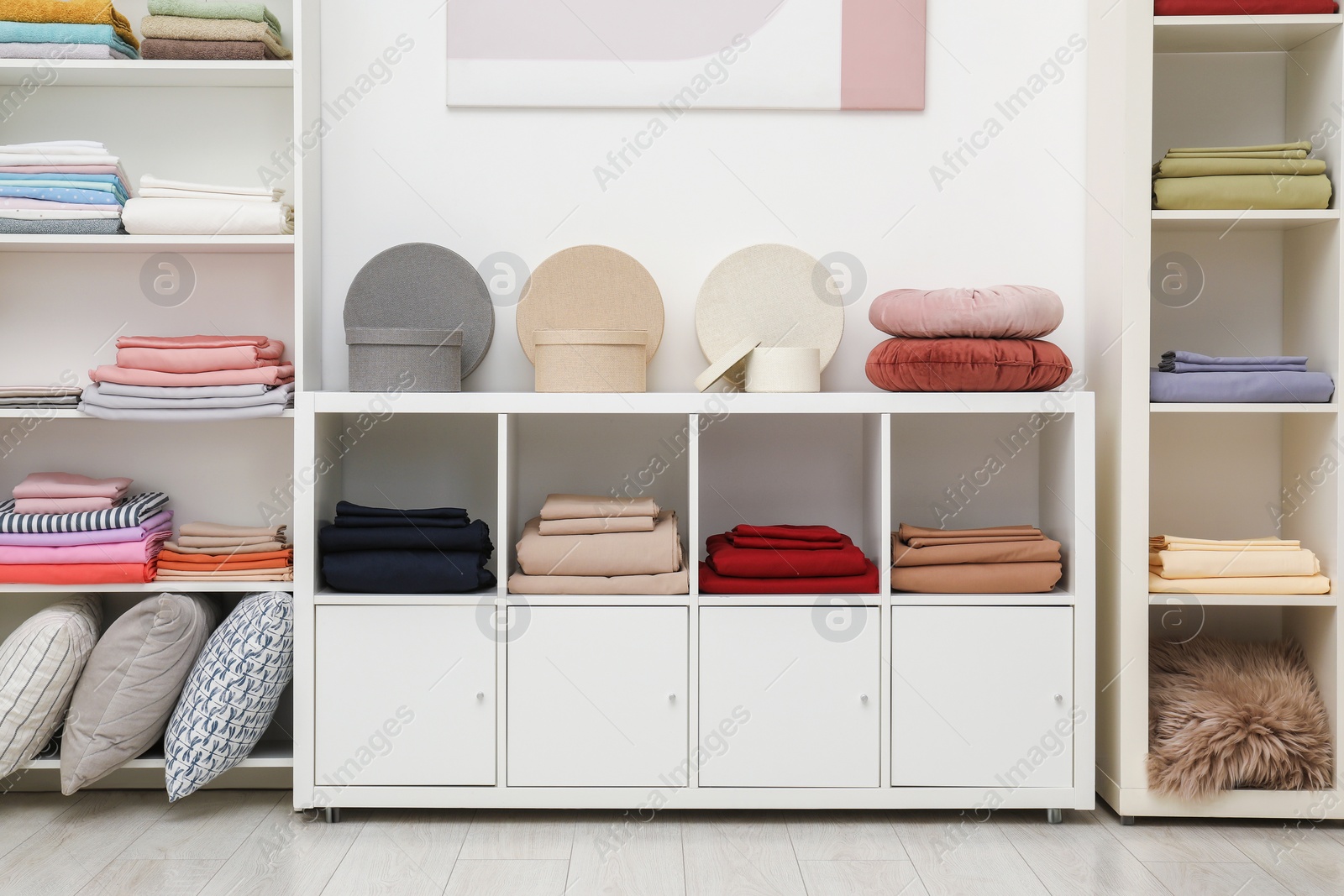 Photo of Decorative boxes, pillows and colorful bed linens in home textiles store